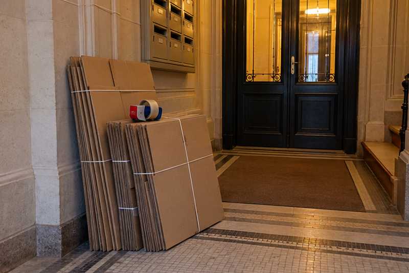 Cartons pliés livrés dans une entrée avec un dévidoir de ruban adhésif