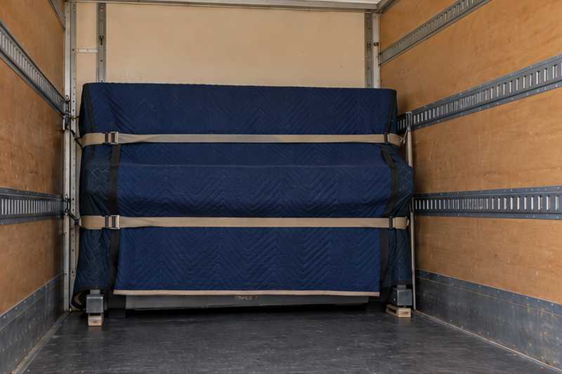 Piano droit sous housse calé contre la paroi d'un camion